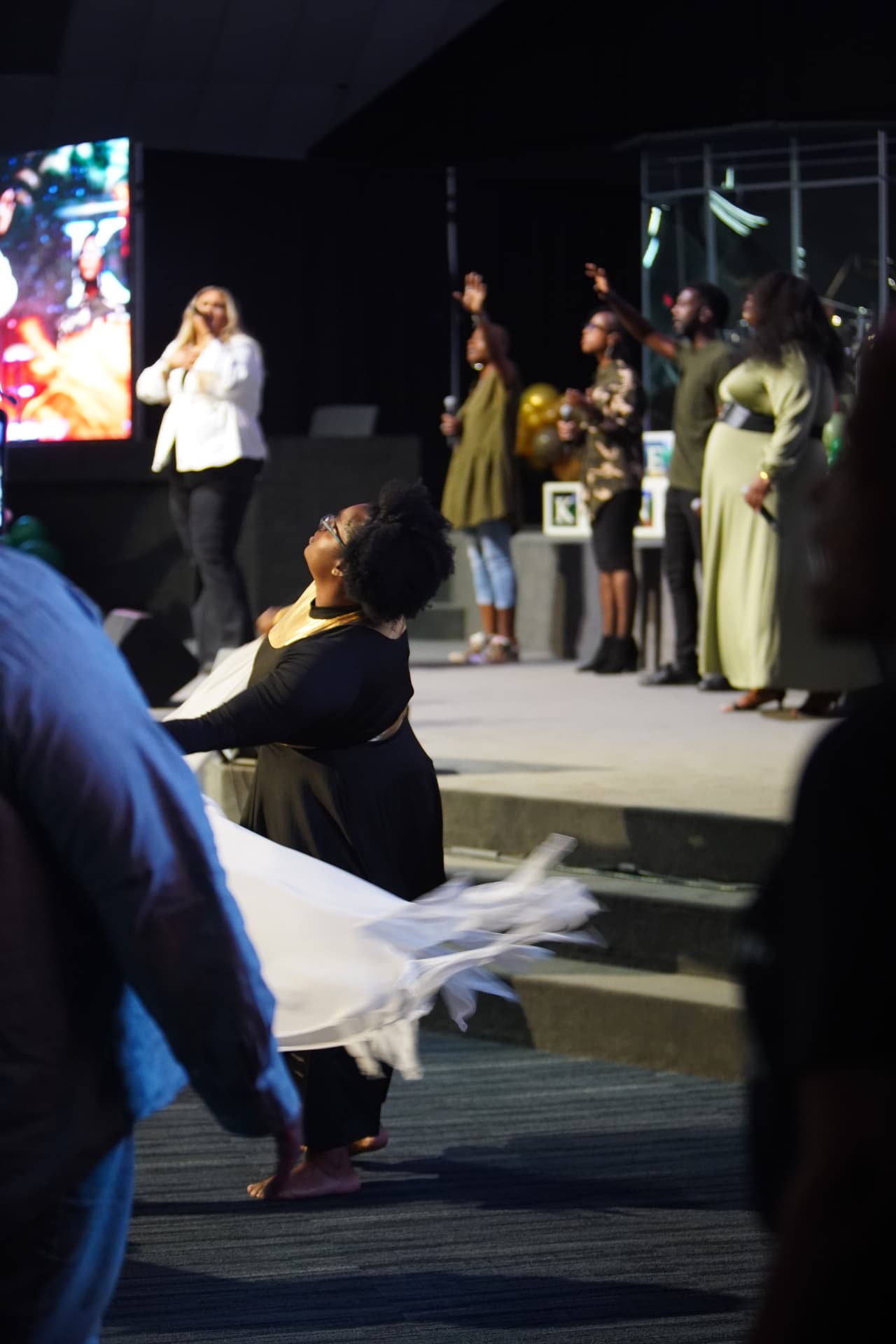 A worship dancer moving with a white banner near the stage