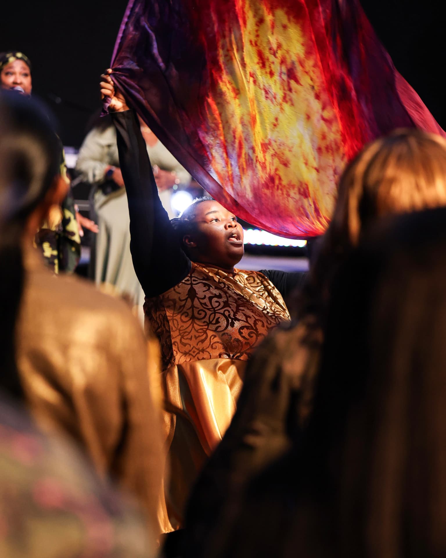 A dancer lifting a fire-colored worship flag