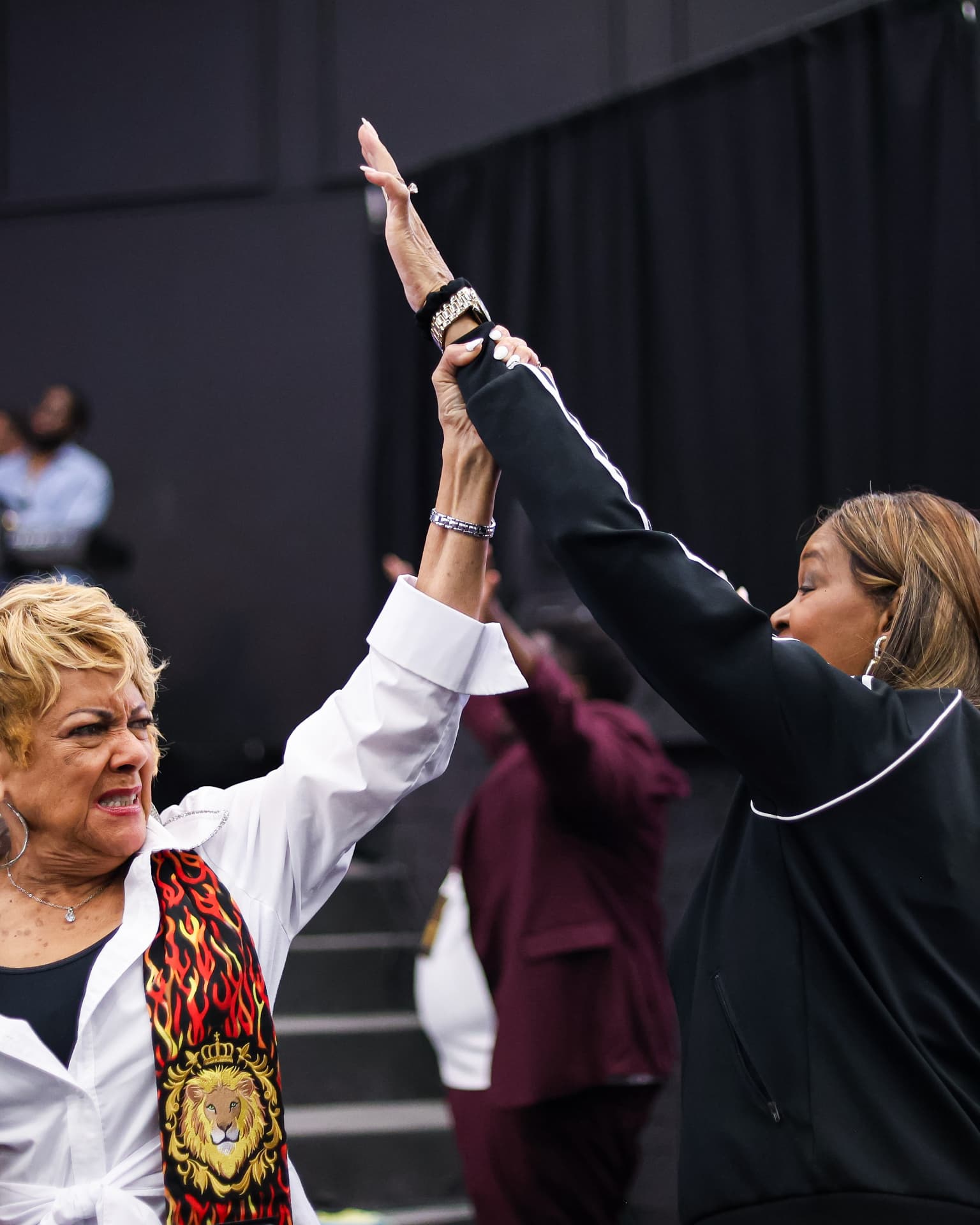 Two women praying together with joined hands lifted high