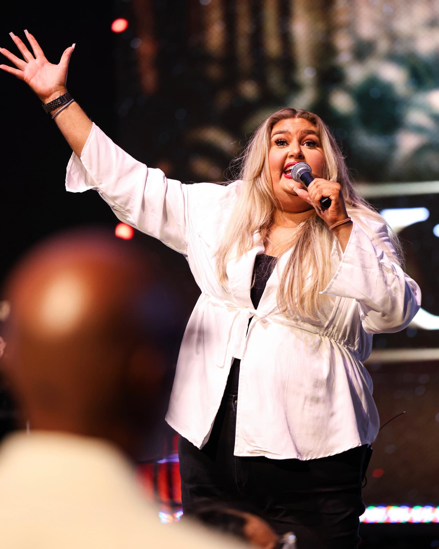 A worship leader singing with one hand lifted